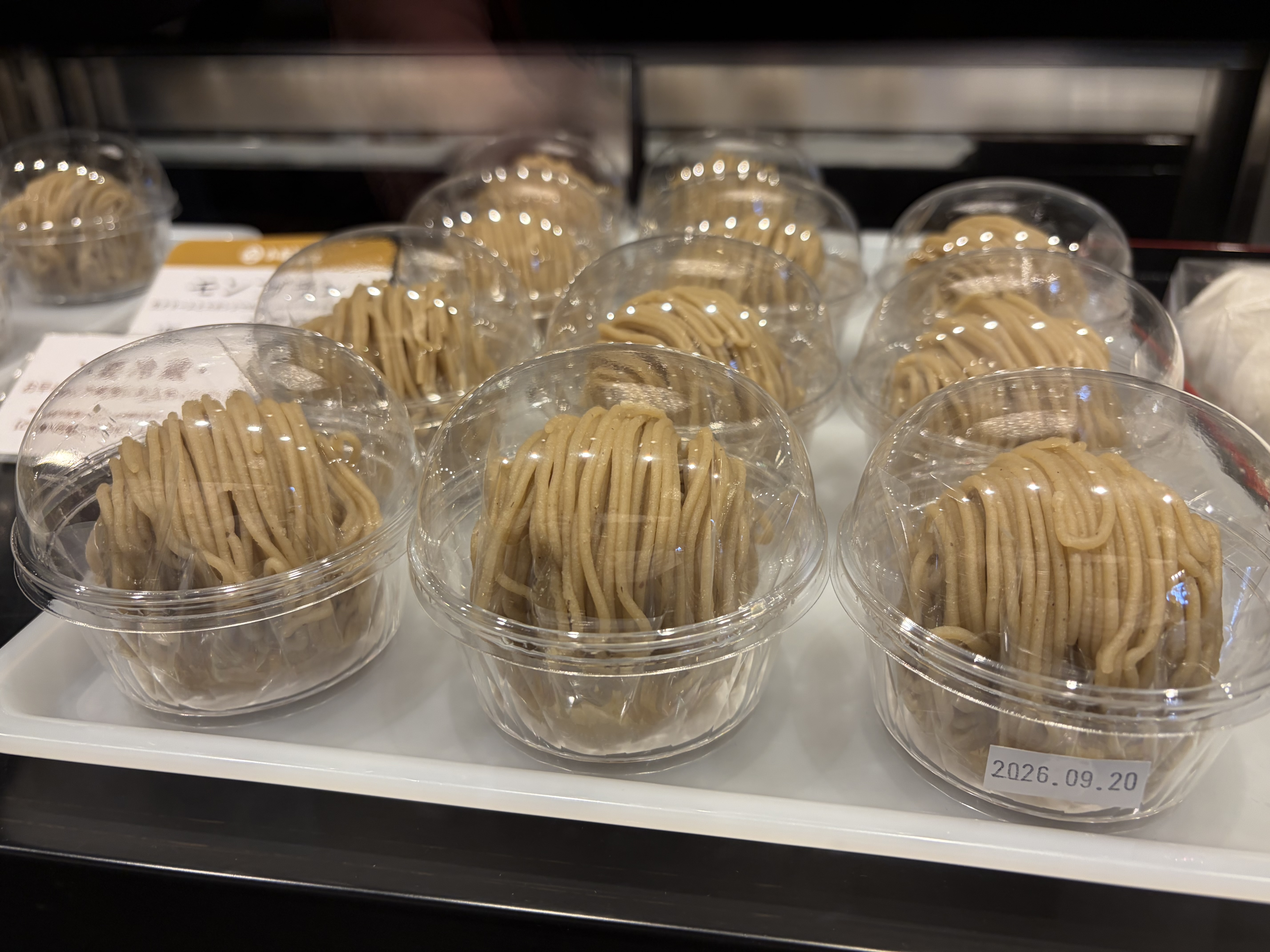 透明な容器に入った、細いクリーム状の飾りが重ねられた淡い茶色の菓子が、ショーケースに並んでいる。