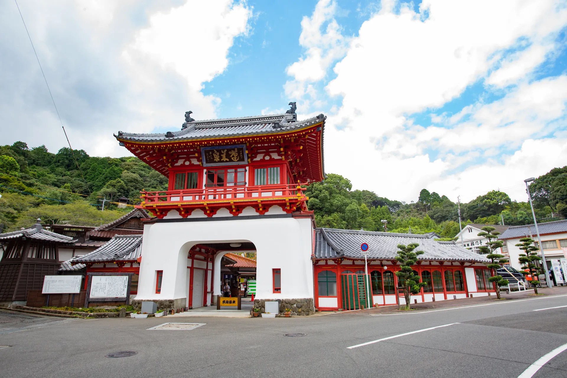 青空を背景に立つ、朱塗りの武雄温泉楼門と周囲の建物