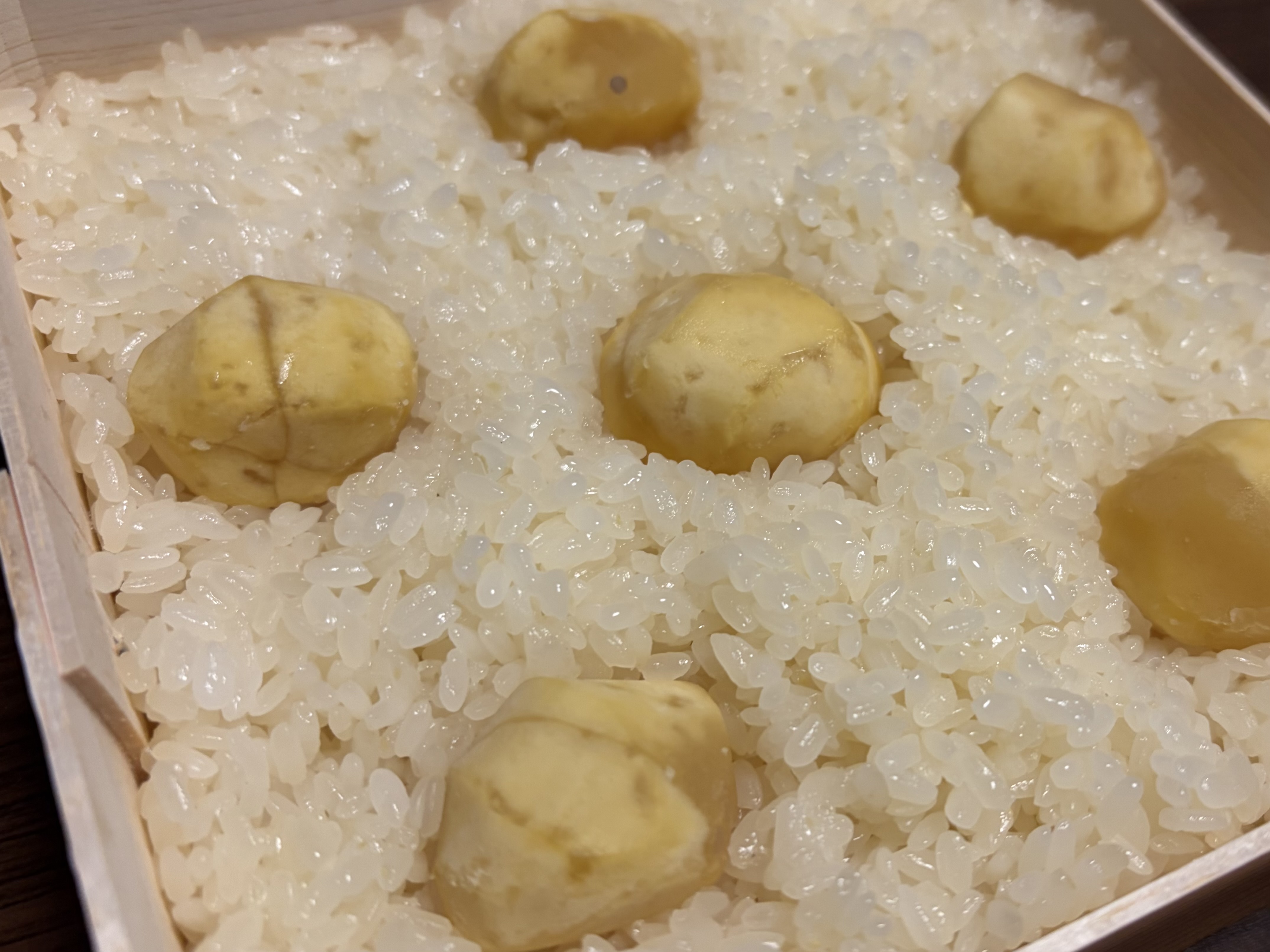 栗がのった白いご飯を木箱に詰めた料理のクローズアップ。