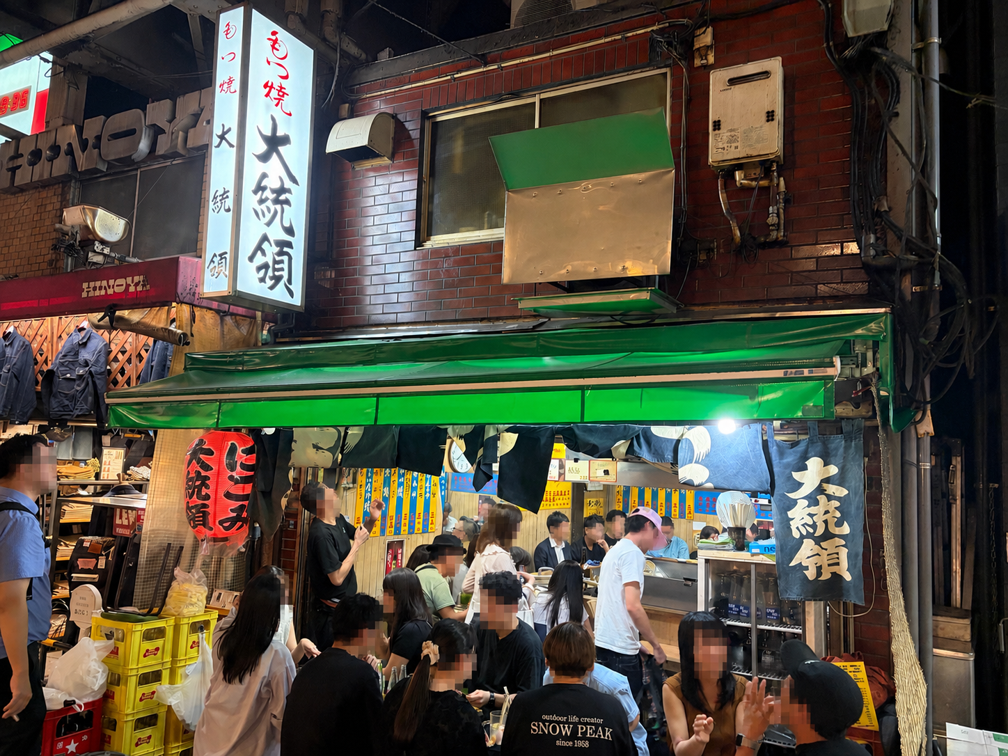 ひさしの下で飲食する客が見える大衆酒場の店頭。